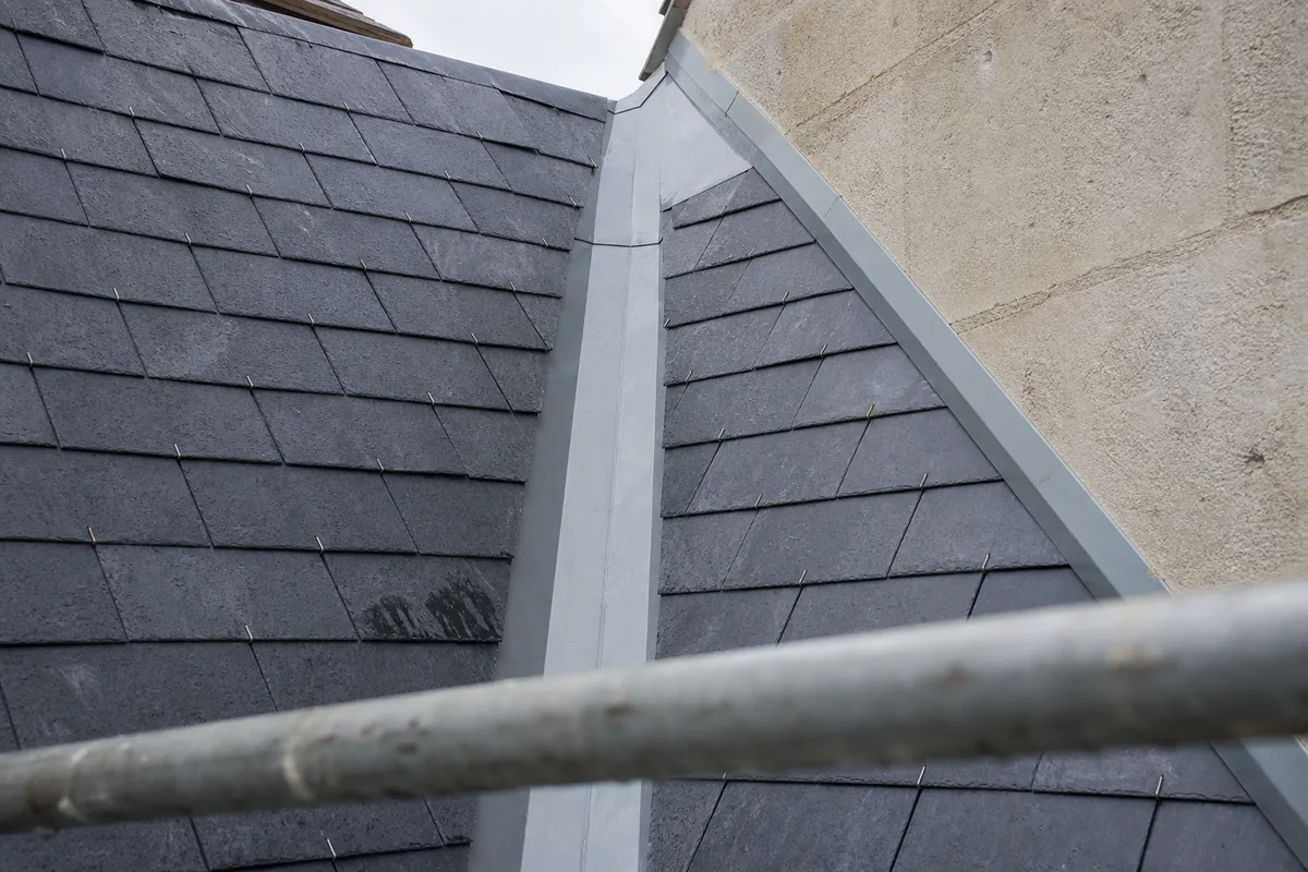 Zinguerie neuve en zinc le long d’une noue d’ardoise sur une maison mitoyenne